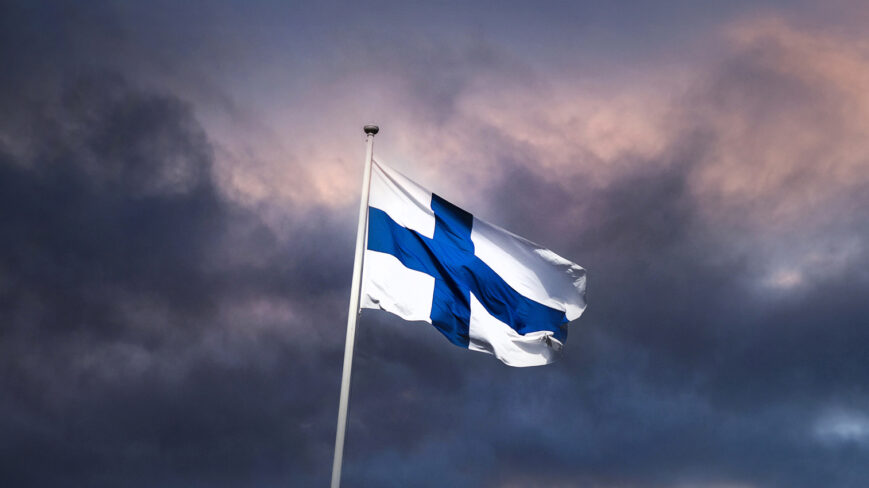 Ilta taivasta vasten salossa liehuva Suomen lippu.