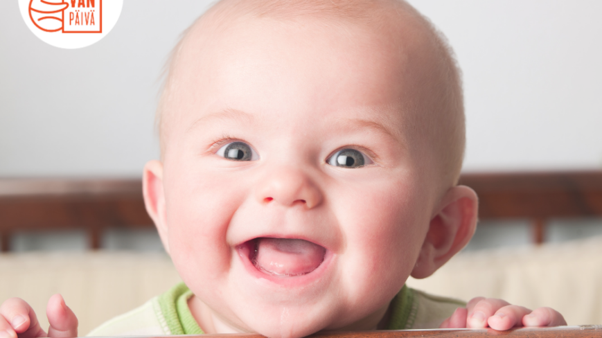 Iloinen vauva leveässä hampaattomassa hymyssä.