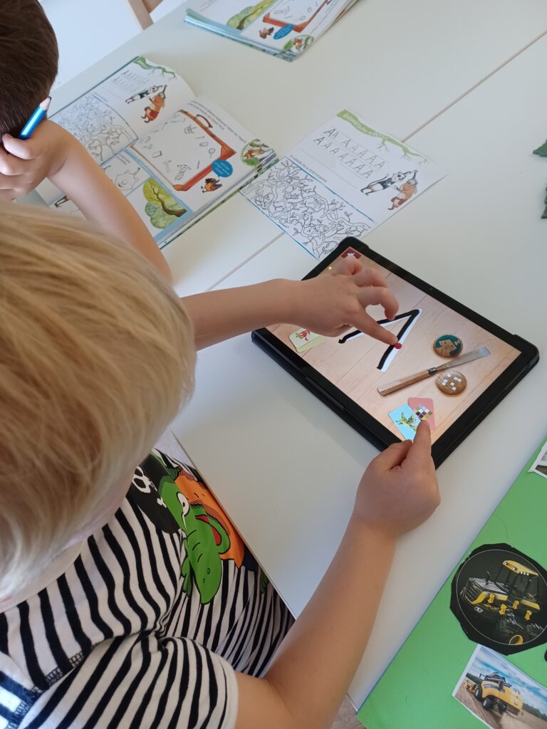 Lapsi harjoittelee tabletin kosketusnäytölle A-kirjainta.