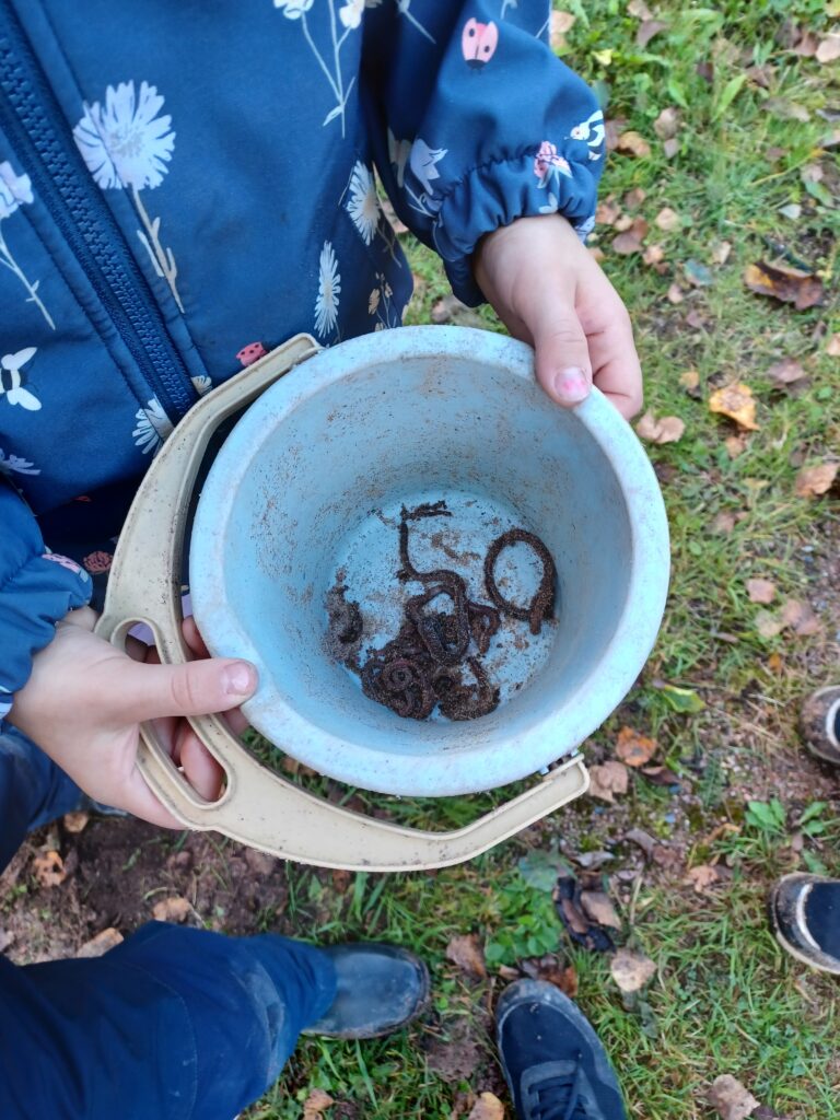 Lapsen käsissä vaaleansininen leikkisanko jossa on kastematoja.