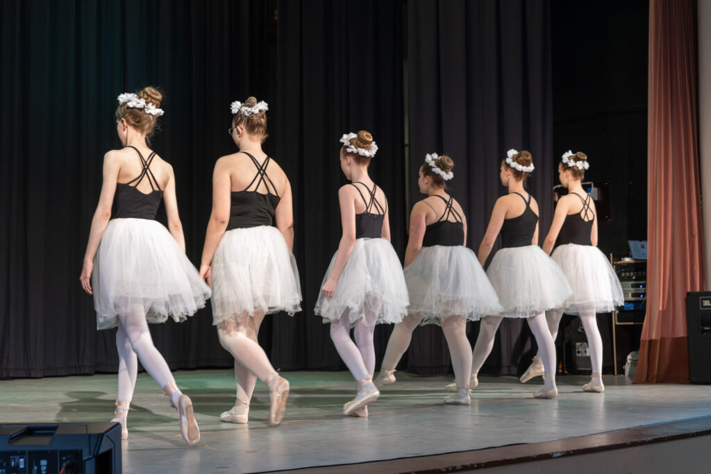 Ballerinat mustavalkoisissa asuissaan selin rivissä näyttämöllä.