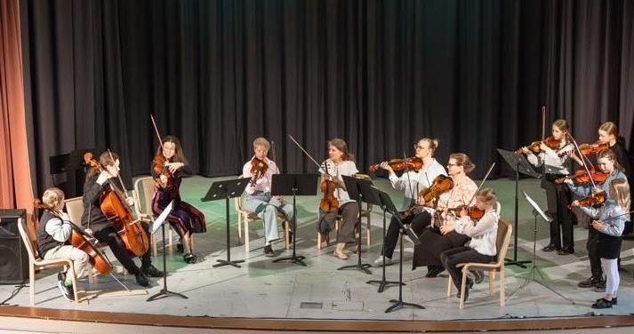 Musiikkiopiston jousisoittajat lavalla Heimolinnassa.