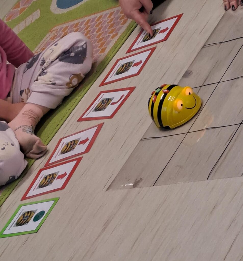 Kuvassa erilaisia robokortteja joissa näytetään miten ohjataan pientä mehiläisroboa pelialustalla. Koodauksen alkeita.