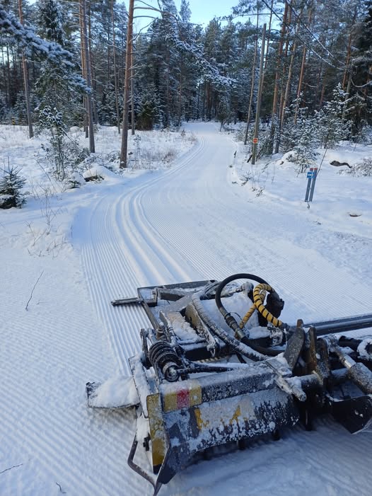 Kuvassa latukone Kertunmäellä ja juuri vedetty latu kirkkaassa säässä.